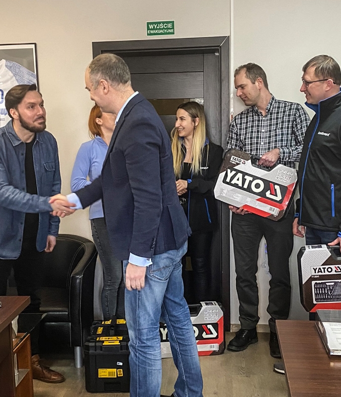 Zdjęcie Tomasza Osuchowskiego wręczającego nagrodę pracownikom firmy INVEST-SUPPORT